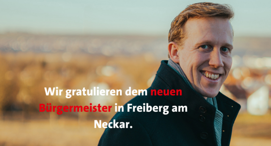 Der neugewählte Bürgermeister von Freiberg am Neckar, Jan Hambach, lächelt in die Kamera. Links davon steht in weißer und roter Schrift: Wir gratulieren dem neuen Bürgermeister in Freiberg am Neckar.